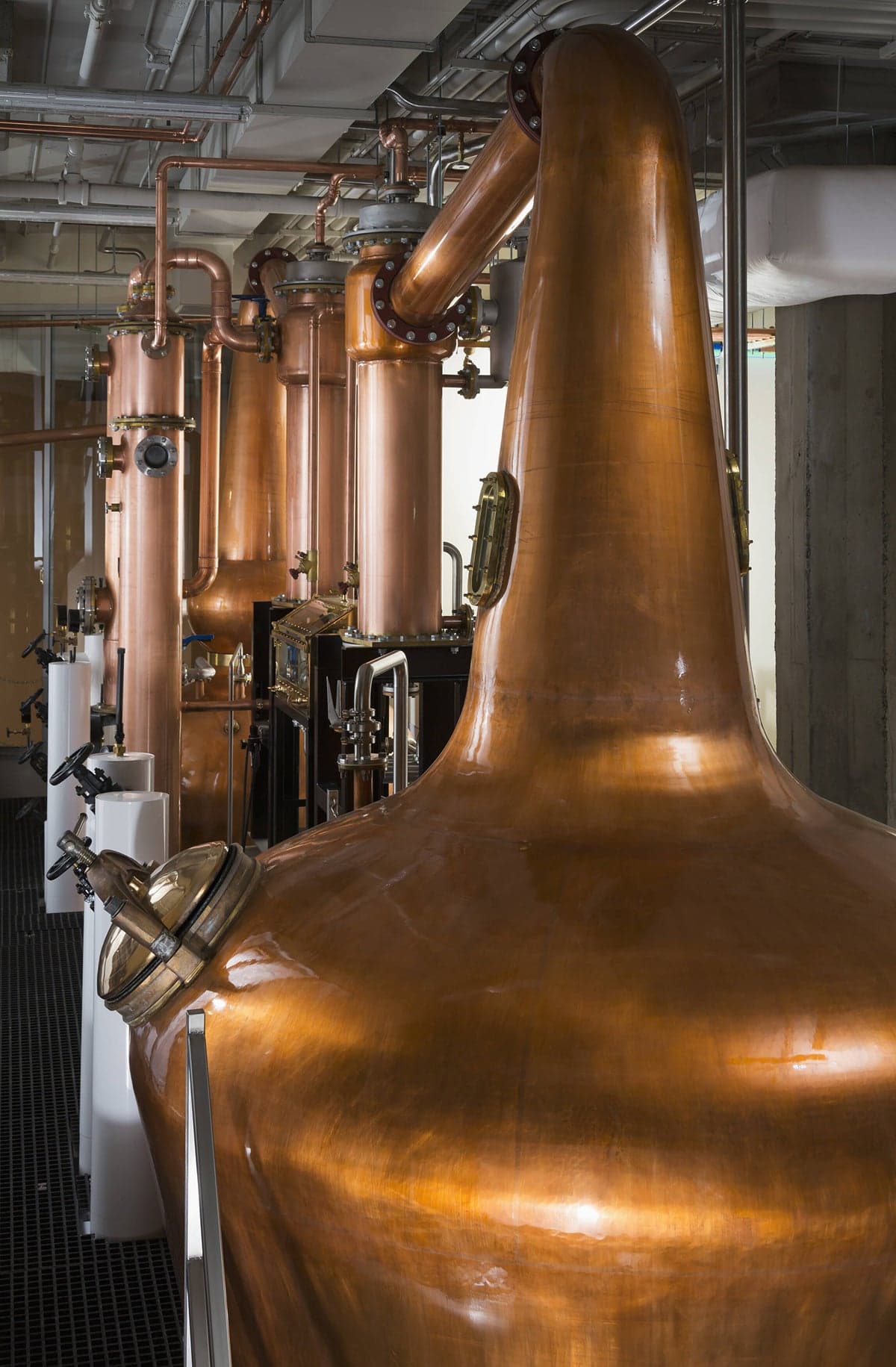Hand-hammered copper pot stills and their columns lined up on the Copperworks distilling floor