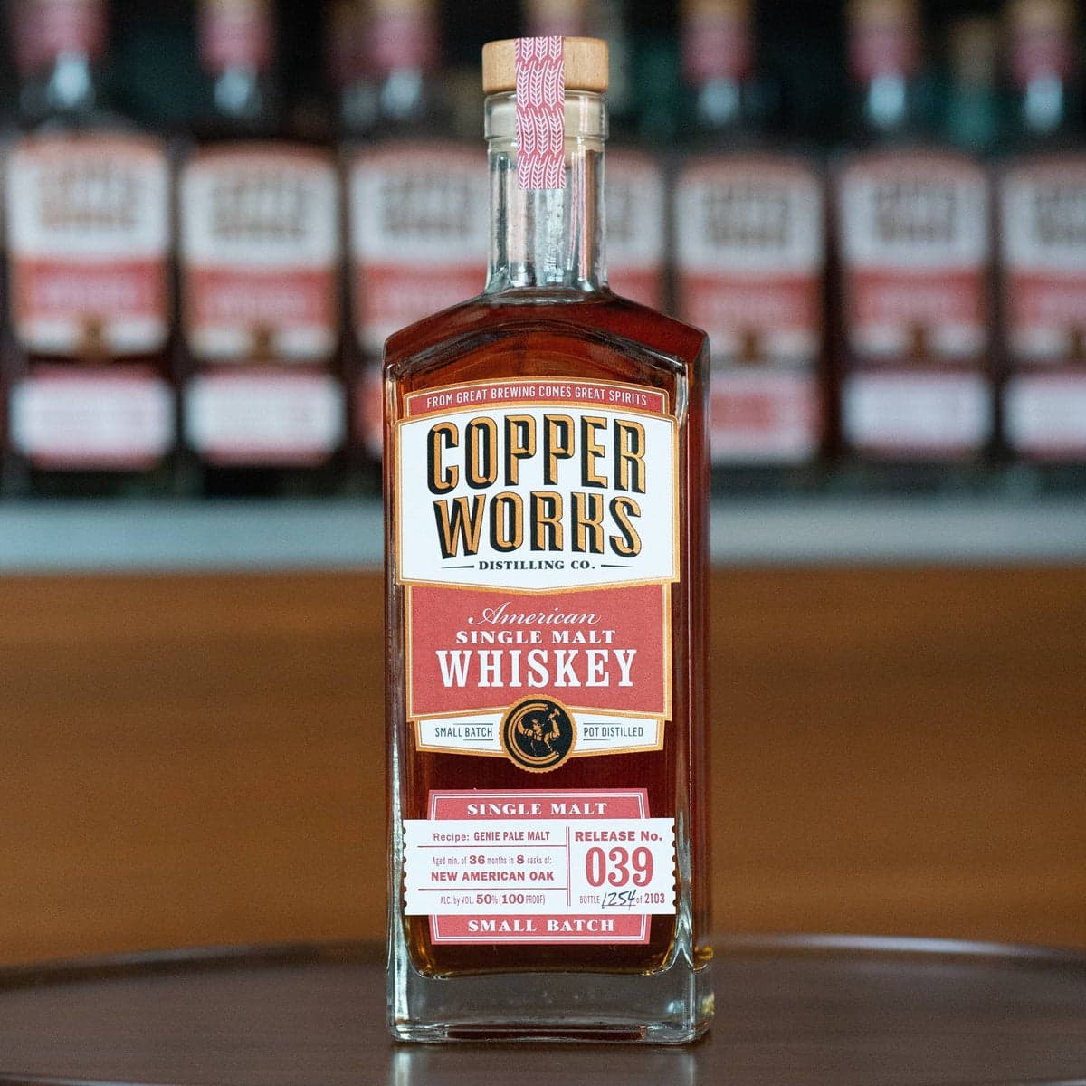 A bottle of Copperworks American Single Malt Whiskey Release No. 039 on the tasting-room bar, more bottles out of focus behind it