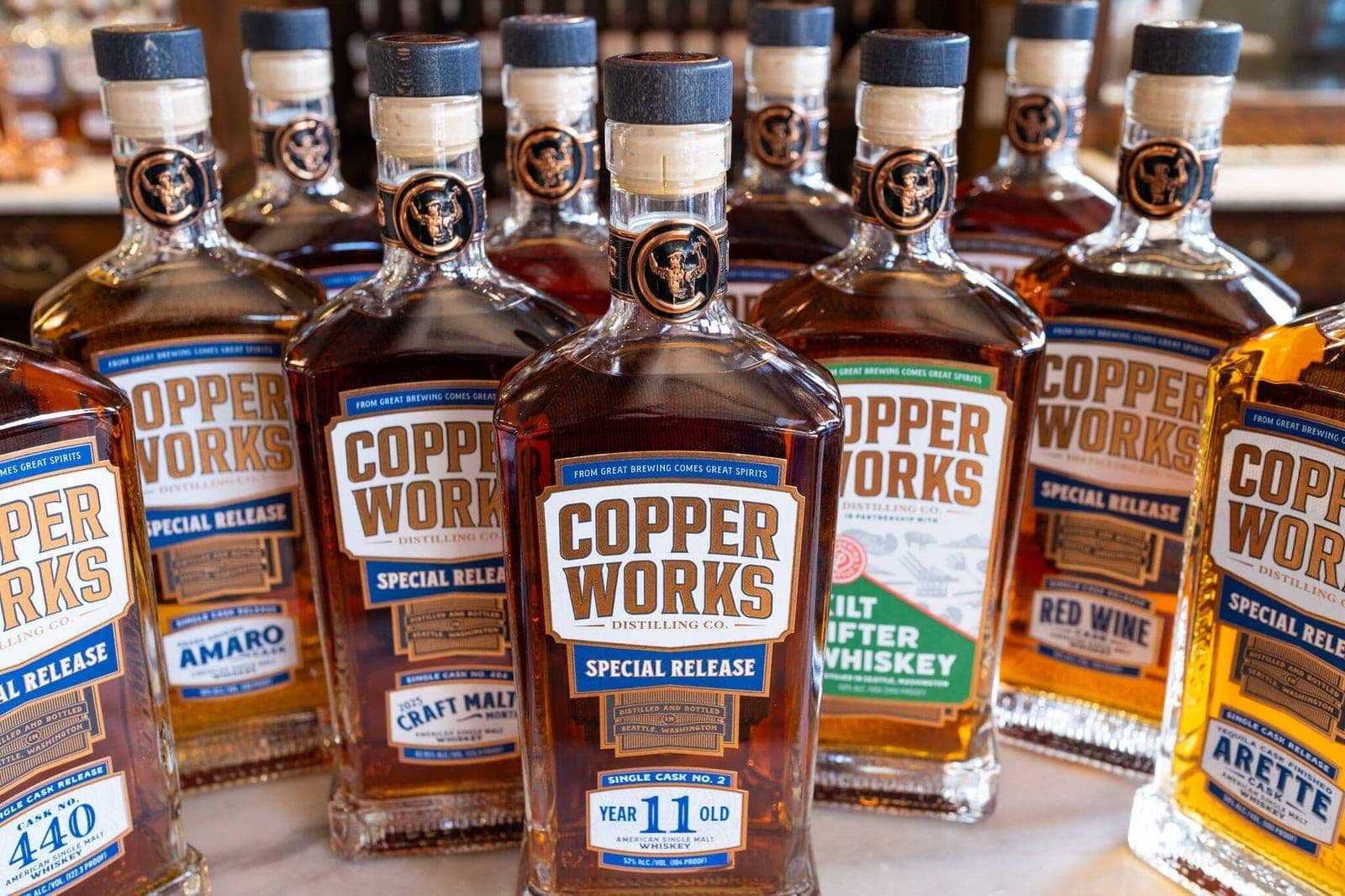Copperworks special release whiskey bottles from 2025 lined up on a bar.