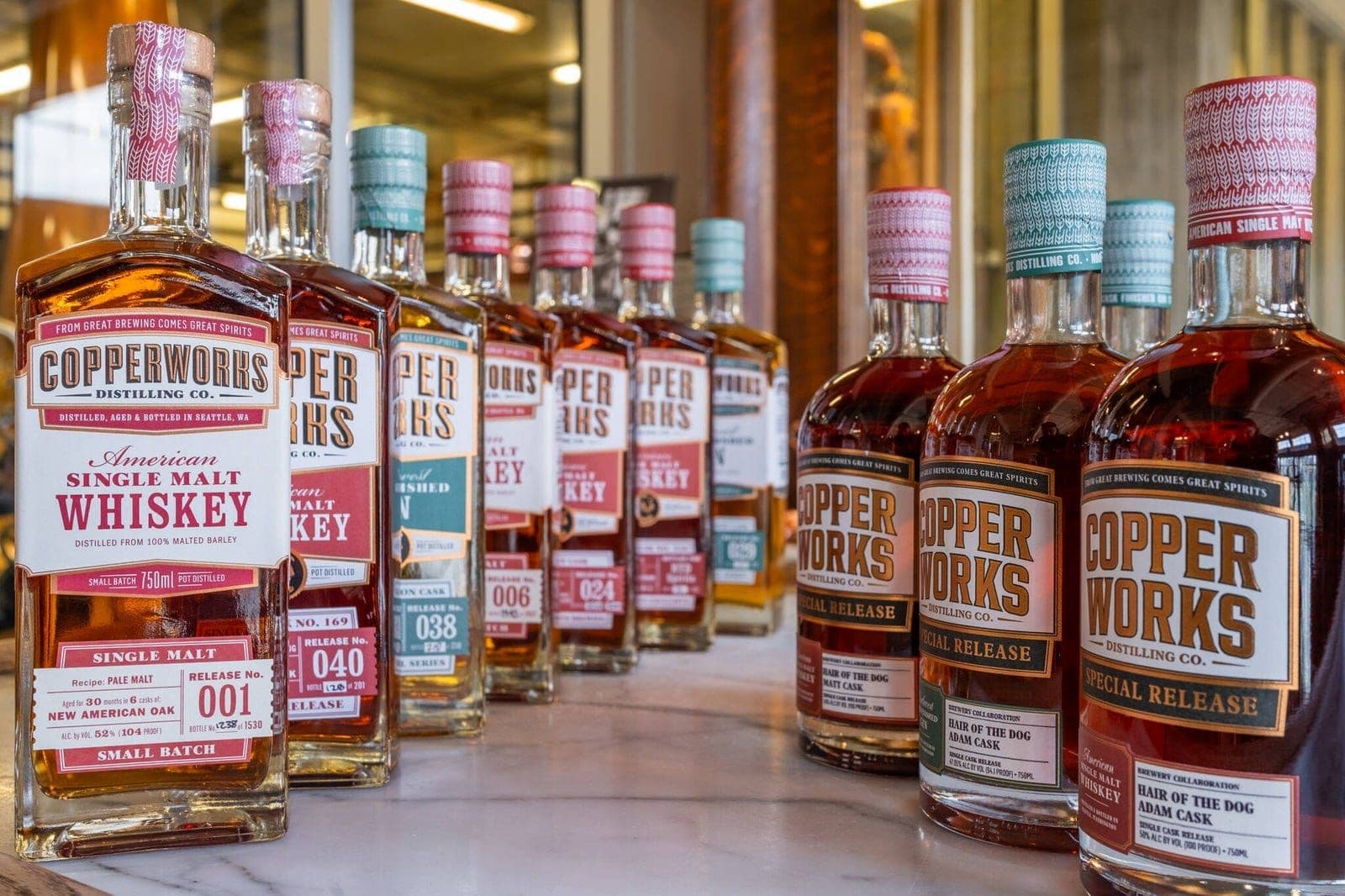 The 2026 archive release lineup: Copperworks whiskey and gin bottles in a row on a bar.