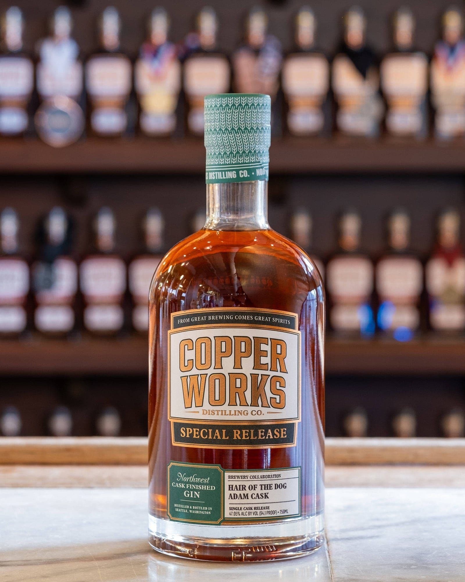 A bottle of Copperworks Hair of the Dog Adam Cask Finished Gin on a bar.