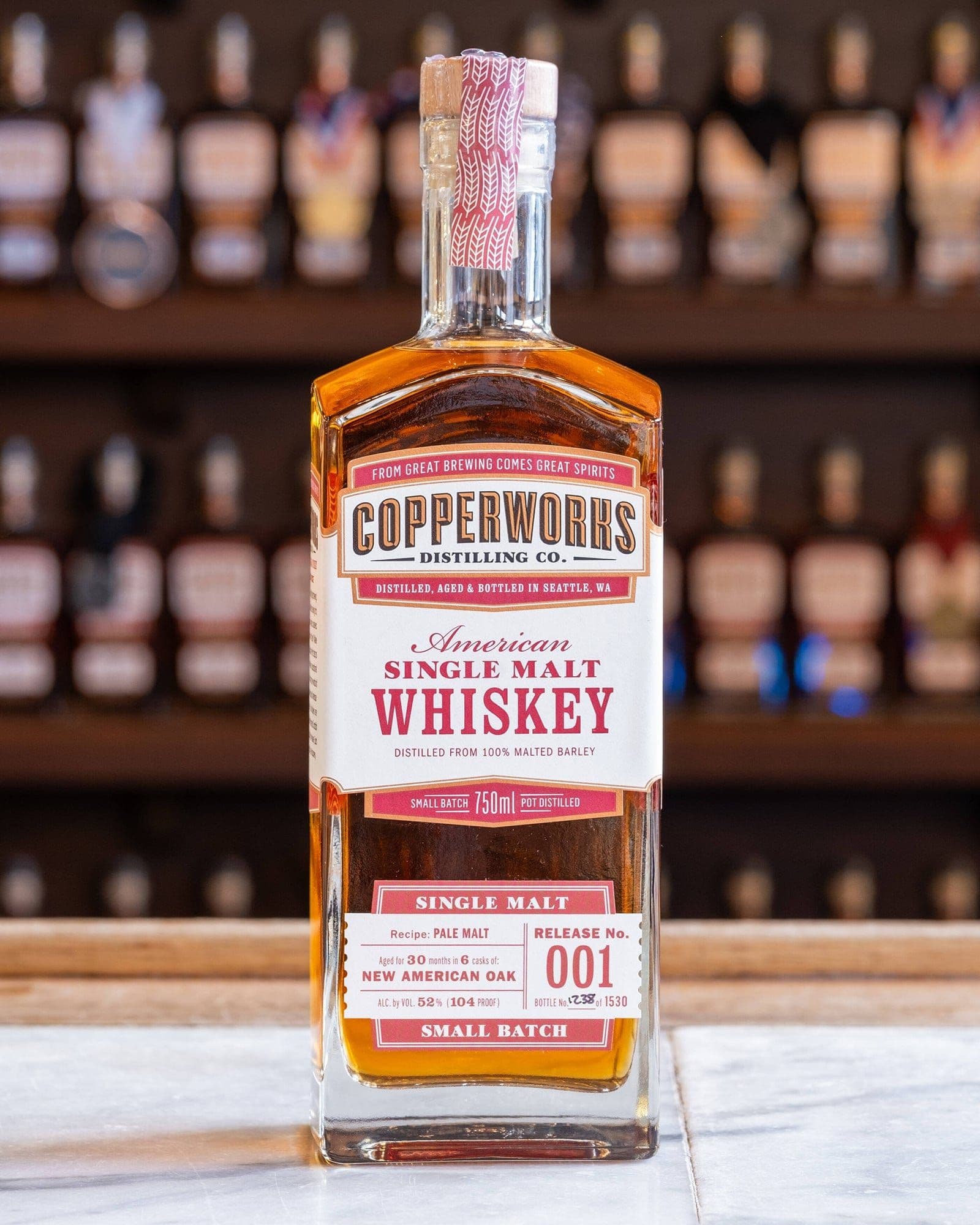 A bottle of Copperworks American Single Malt Whiskey Release No. 001 on a bar.