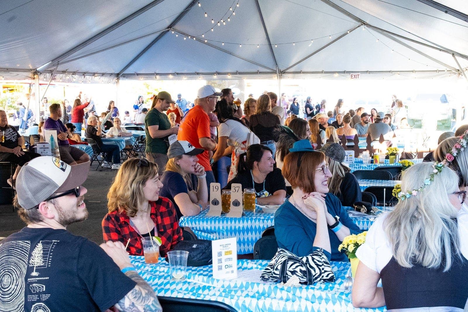 Guests at long tables under a festival tent at an Oktoberfest celebration.