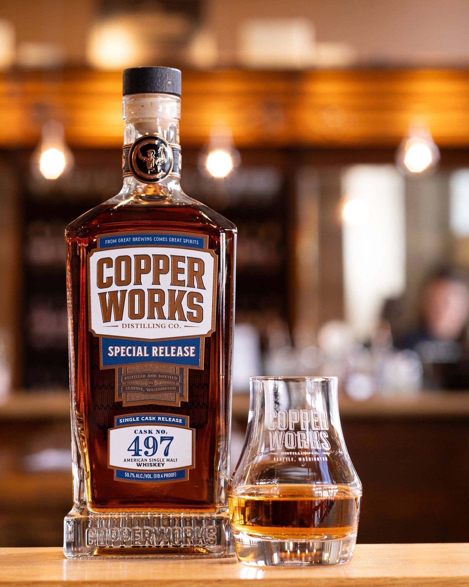 A bottle of Copperworks Single Cask No. 497 beside a tasting glass of whiskey.